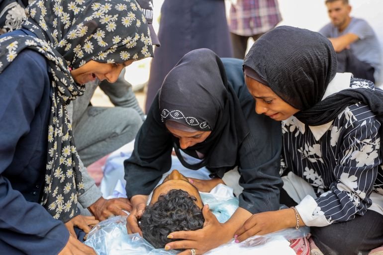 EDITORS NOTE: Graphic content / Women mourn over the body of a man killed during overnight Israeli bombardment on June 12, 2025, at Al-Shifa hospital in Gaza City, amid the ongoing war between Israel and the Palestinian Hamas militant group.