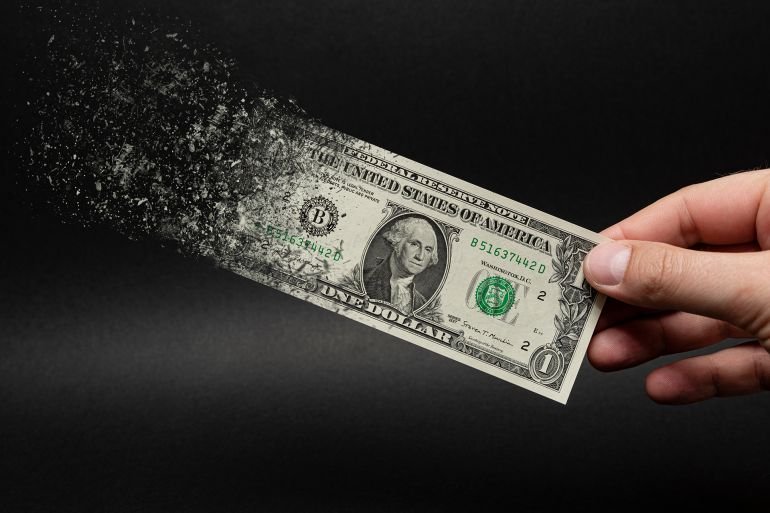 Inflation, dollar hyperinflation with black background. One dollar bill is sprayed in the hand of a man on a black background. The concept of decreasing purchasing power, inflation.