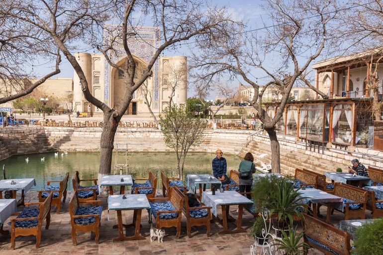 Bukhara, Uzbekistan - March 27, 2024: People are at the Lab-i Hauz Khanqah square, Nadir Divan-Beghi madrasa is on the background; Shutterstock ID 2627087131; purchase_order: aj; job: ; client: ; other: