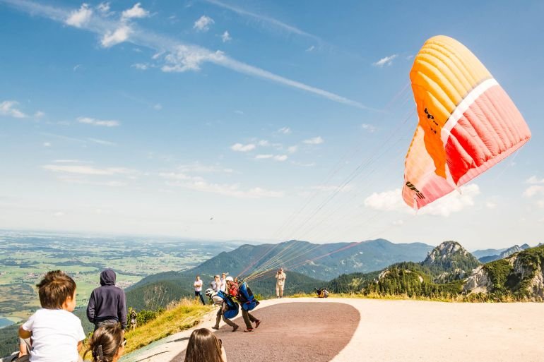 SCHWANGAU, GERMANY - AUGUST 23: Unknown paraglider on mount Tegelberg in Schwangau, Germany on August 23, 2015. Tegelberg is one of the most popular paragliding areas in Germany.; Shutterstock ID 330298130; purchase_order: aj; job: ; client: ; other: