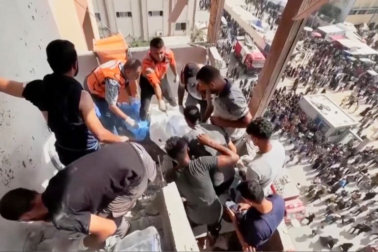 This frame grab taken from a video released by Reuters shows several people trying to remove a body from the the outside stairs of Nasser Hospital shortly after the first of two rounds of Israeli strikes in Khan Younis, southern Gaza Strip, Monday, Aug. 25, 2025. (Reuters via AP)