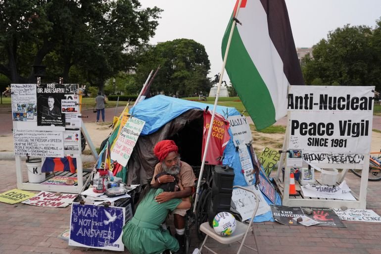 Philipos Melaku-Bello comforts a woman as he sits on his regular spot at the 44-year-old White House Peace Vigil outside of the White House, after U.S. President Donald Trump ordered its removal, following the deployment of the National Guard and increased presence of federal law enforcement to assist in crime prevention, in Washington, D.C., U.S., September 5, 2025. REUTERS/Leah Millis