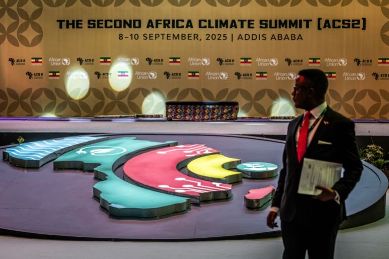 A delegate stands in front of a backdrop for the Second Africa Climate Summit (ACS2) during the opening of the High-Level Leaders Summit in Addis Ababa, on September 8, 2025. (Photo by Luis TATO / AFP)