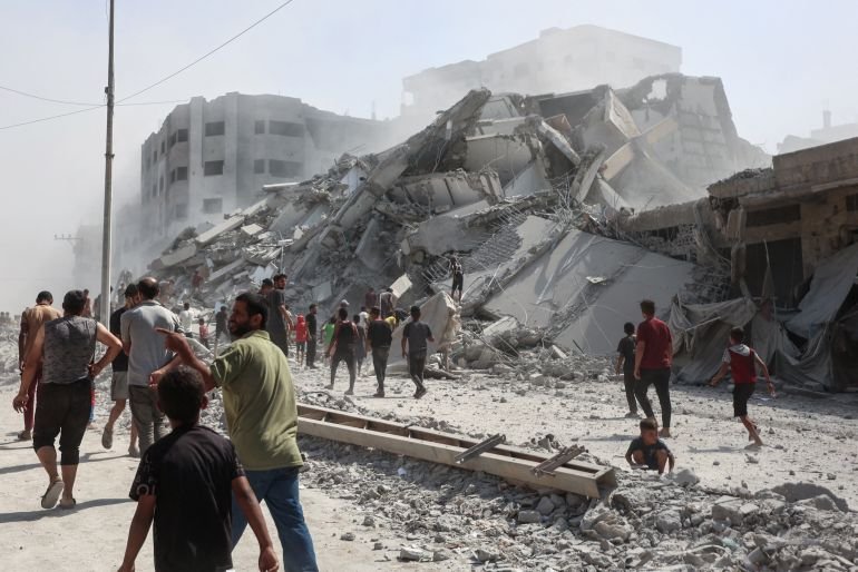 فلسطينيون يبحثون عن ناجين بين ركام برج الغفاري المدمر إثر قصف إسرائيلي عنيف (الفرنسية)