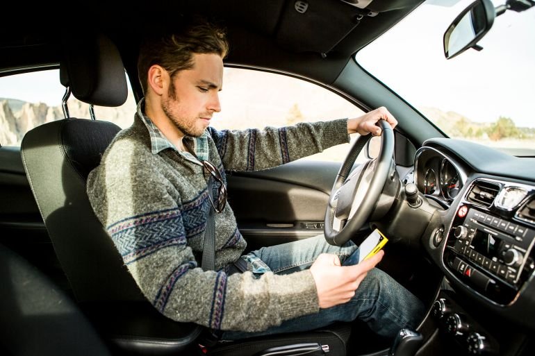 A man sending a text while driving.