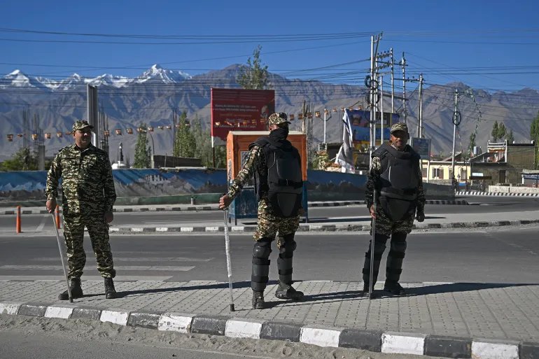 Security personnel stand guard along a road during a curfew in Leh on September 28, 2025