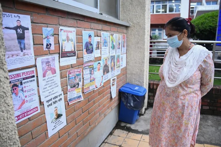 A woman looks at photographs of the missing following flash floods in Nepal, outside a hospital in Kathmandu on August 29, 2026.
