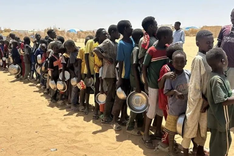 مشهد أطفال نازحين يصطفون في طابور طويل أمام _التكية_ بمخيم طويلة