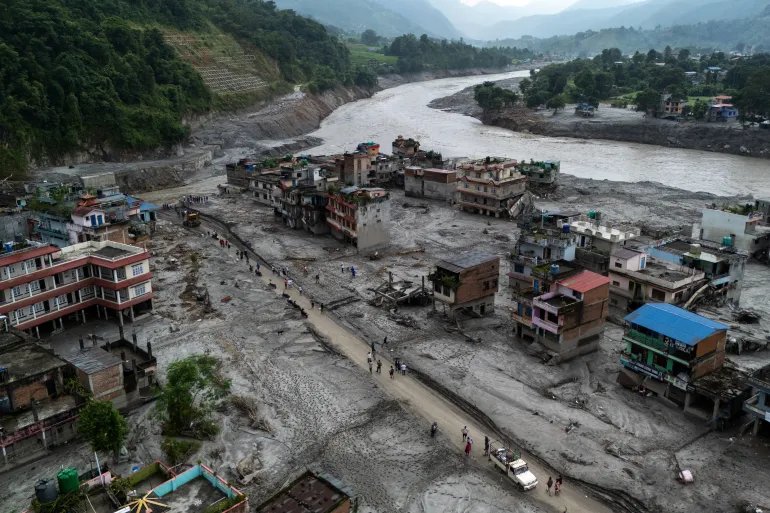 A drone view of people walking on a road and houses in mud, following deadly flash floods and mudslides at Devighat, Nuwakot district, Nepal, August 29, 2026. REUTERS/Athit Perawongmetha