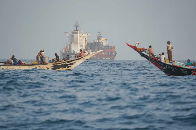 People sail their boats past container ships anchoring near the Strait of Bab al-Mandeb off Yemen's coast in the Gulf of Aden on August 6, 2026. (Photo by AFP) / ATTENTION EDITORS: AFP COVERS THE WAR IN THE MIDDLE EAST THROUGH ITS EXTENSIVE REGIONAL NETWORK, INCLUDING BUREAUS IN TEHRAN, JERUSALEM, AND SEVERAL NEIGHBORING COUNTRIES. SINCE THE START OF THE CONFLICT, JOURNALISTS HAVE BEEN WORKING UNDER INCREASINGLY RESTRICTIVE CONDITIONS. AUTHORITIES IN SEVERAL COUNTRIES HAVE LIMITED REPORTERS' MOVEMENTS, PHOTO AND LIVE VIDEO COVERAGE FROM SENSITIVE LOCATIONS. SOME GOVERNMENTS AND ARMED GROUPS HAVE BANNED IMAGES OF MISSILE OR DRONE STRIKES AND OTHER SECURITY-RELATED SITES.
