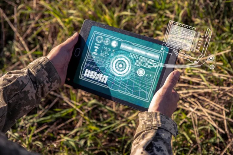 AI technology in the army. Warfare analytic operator checking coordination of the military team. Military commander with a digital tablet device with artificial intelligence operating troops outdoors.