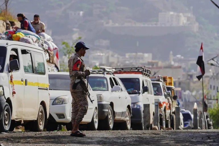 A Houthi fighter stands at a checkpoint to manage the line of cars departing from the city toward Houthi-controlled areas via the eastern corridor, ahead of the Islamic Eid al-Adha, or Feast of the Sacrifice, in Taiz, Yemen, Tuesday, May 26, 2026. (AP Photo/Abdulnasser Alseddik)