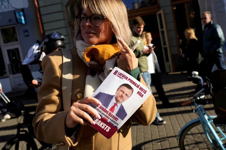FILE PHOTO: A woman holds an election campaign leaflet of the "Latvia First" party with a picture of the party's leader, Ainars Slesers, before the general election in Riga, Latvia, September 27, 2026. REUTERS/Ints Kalnins/File Photo
