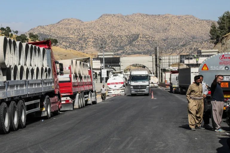 This photo taken on September 21, 2026 shows Iranian trucks waiting to cross back into Iran in the Penjwen district, near the border with Iran in Iraq's autonomous Kurdistan region. For months, drones and missiles have buzzed over the lush green hometown of Penjwen bordering Iran, as the Islamic republic and the United States fight a war that has engulfed most of the region. Iran and its allied Iraqi armed factions have intensified attacks on bases hosting US troops, as well as against Iranian Kurdish opposition groups, whose fighters have long sought refuge in Kurdistan's mountains. (Photo by Safin HAMID / AFP) / TO GO WITH 'WAR-IRAN-US-ISRAEL-IRAQ-KURDS, FOCUS' BY SHWAN MOHAMMED