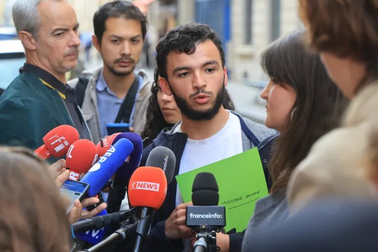رياض راني المتحدث باسم الحراك الطلابي الفرنسي Secretary General of l'Union syndicale lycéenne (USL) Ryad Rani (C) speaks to the press following a meeting between representatives of student organisations and France's Education Minister in front of the ministry in Paris on October 2, 2026, amid student protests over a range of grievances that began last week. (Photo by Ludovic MARIN / AFP)