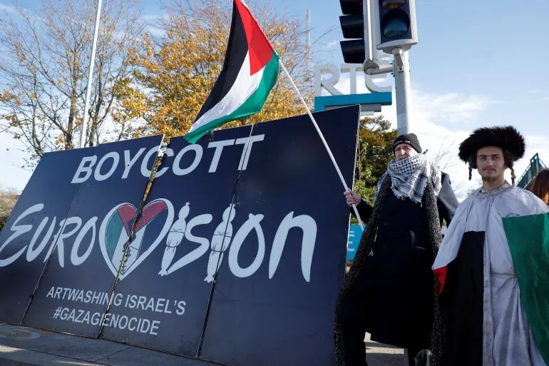 Pro-Palestinian protestors hold a flag and a banner outside the RTE (Radio Telefis Eireann) Irish public service broadcaster television studios as demonstrators call for an Irish boycott of the 2026 Eurovision Song Contest if there is Israeli participation, in Dublin, Ireland, November 1, 2025. REUTERS/Clodagh Kilcoyne