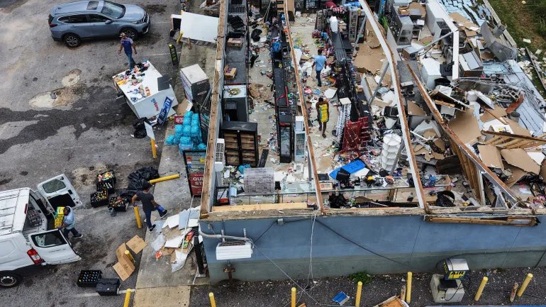 People salvage the contents of their destroyed mini mart in the aftermath of Hurricane Isaias in Milton, Fla., Saturday, Oct. 10, 2026. (AP Photo/Gerald Herbert)