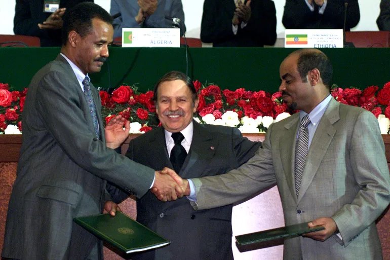 الرئيس الإريتري أسياس أفورقي (يسار) ورئيس الوزراء الإثيوبي ملس زيناوي يتصافحان عقب توقيع اتفاق السلام في الجزائر في ديسمبر/كانون الأول 2000